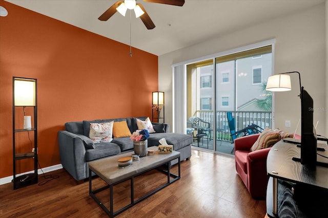 living room featuring a ceiling fan, vaulted ceiling, baseboards, and wood finished floors