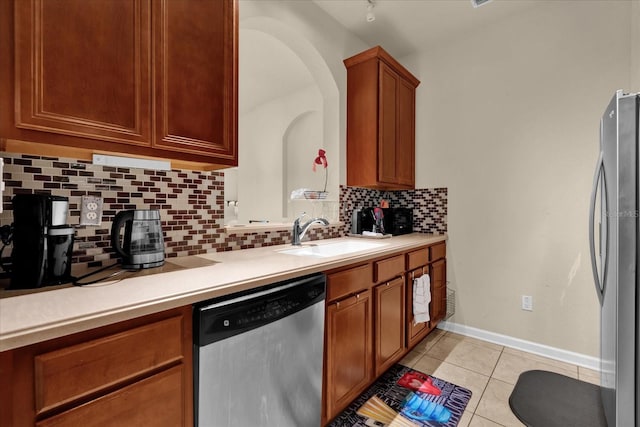 kitchen with appliances with stainless steel finishes, brown cabinets, light countertops, and a sink