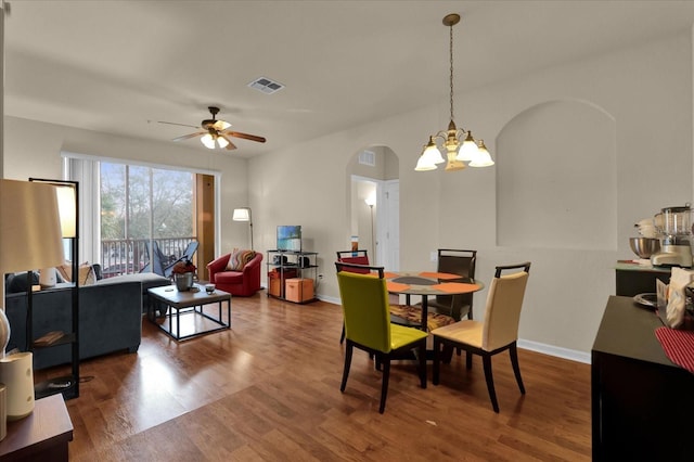 dining space with arched walkways, baseboards, visible vents, ceiling fan with notable chandelier, and wood finished floors