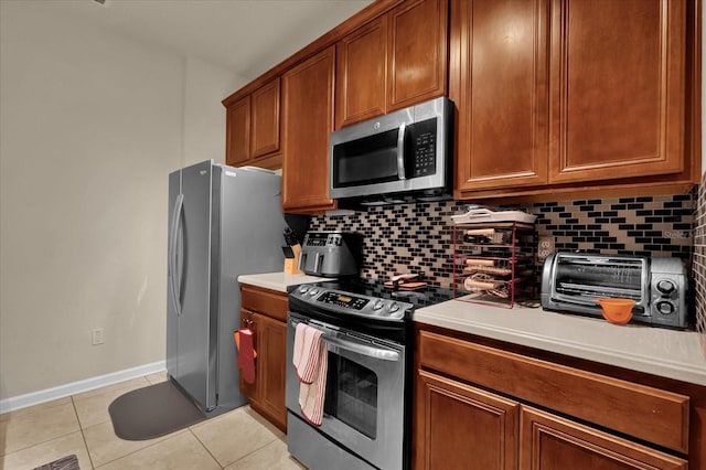 kitchen with a toaster, tasteful backsplash, stainless steel appliances, and light tile patterned floors