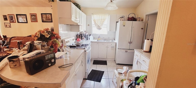 kitchen featuring white cabinetry, sink, light tile patterned floors, and white appliances