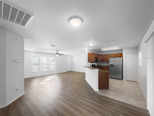 kitchen featuring a center island, a textured ceiling, light wood-type flooring, appliances with stainless steel finishes, and ceiling fan