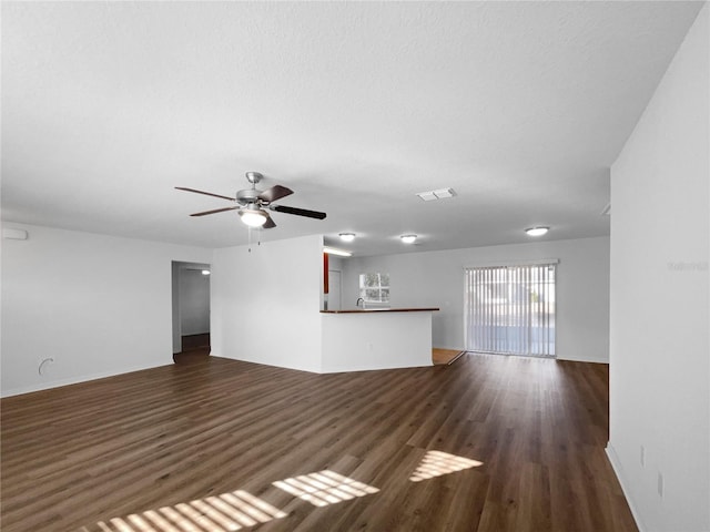 unfurnished living room featuring dark hardwood / wood-style flooring, a textured ceiling, and ceiling fan