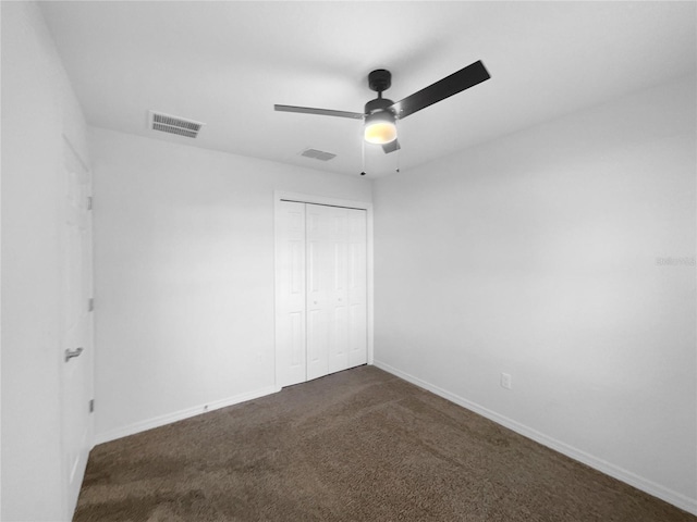 unfurnished bedroom with dark colored carpet, ceiling fan, and a closet