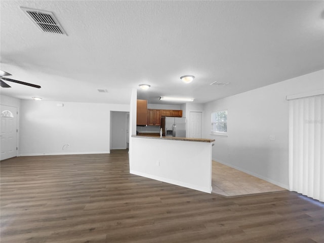 kitchen with stainless steel refrigerator with ice dispenser, ceiling fan, dark hardwood / wood-style flooring, and a textured ceiling