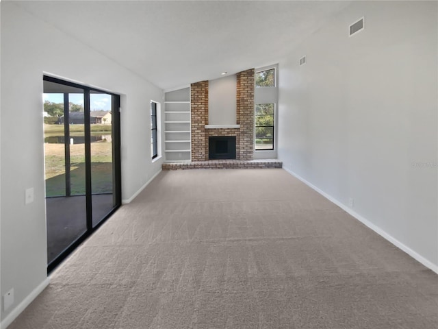 unfurnished living room featuring lofted ceiling, carpet flooring, built in features, and a brick fireplace