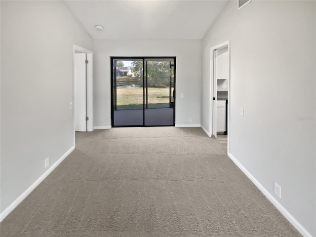 empty room featuring light colored carpet and vaulted ceiling