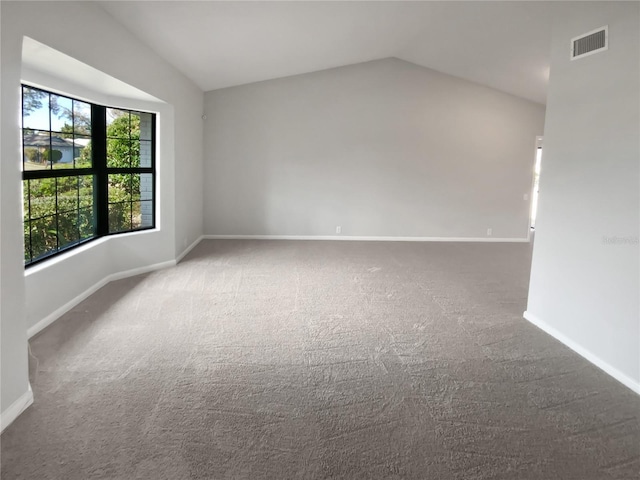 carpeted empty room with vaulted ceiling