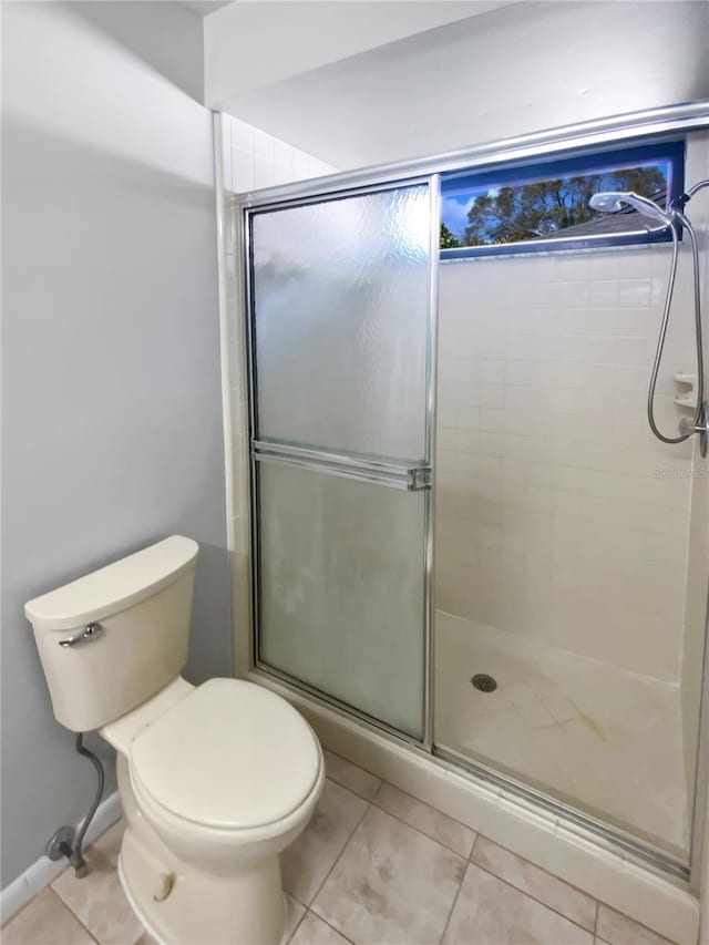 bathroom with tile patterned floors, a shower with door, and toilet