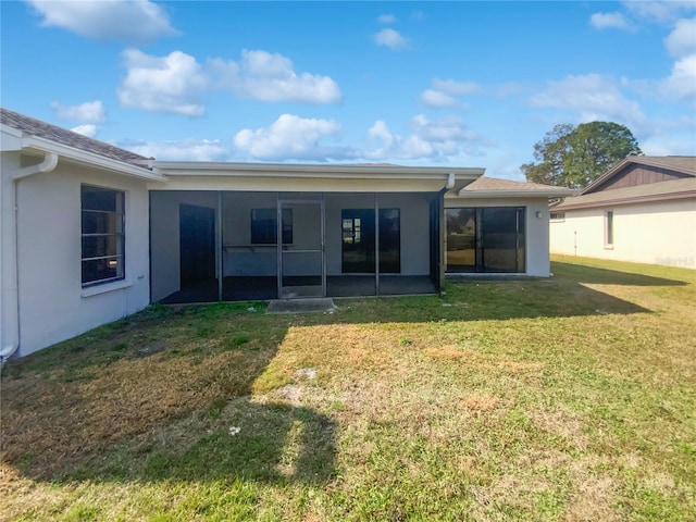 rear view of house featuring a yard and a sunroom