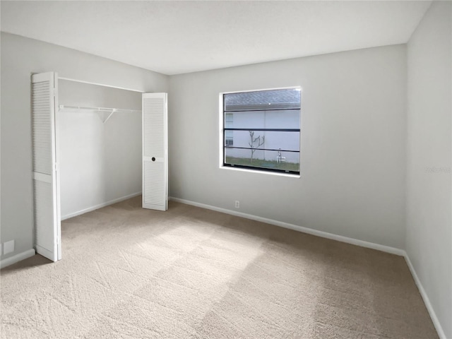 unfurnished bedroom with light colored carpet and a closet