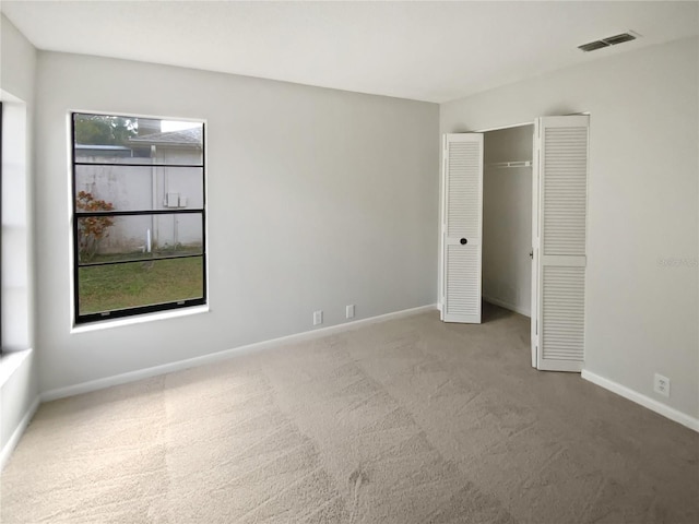 unfurnished bedroom with light carpet and a closet