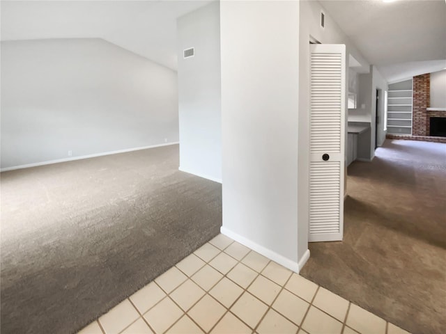 hall featuring built in features, lofted ceiling, and light carpet