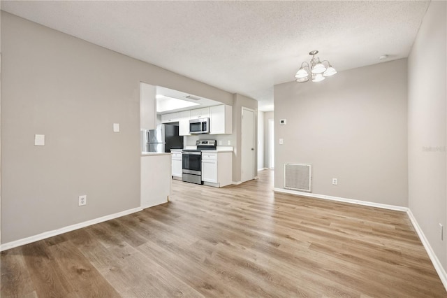 353 E Orange St, Altamonte Springs, FL 32701 - unfurnished living room featuring an inviting chandelier, light hardwood / wood-style flooring, and a textured ceiling