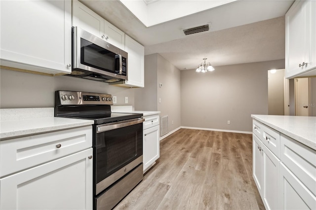 353 E Orange St, Altamonte Springs, FL 32701 - kitchen with appliances with stainless steel finishes, white cabinetry, light wood-type flooring, hanging light fixtures, and an inviting chandelier