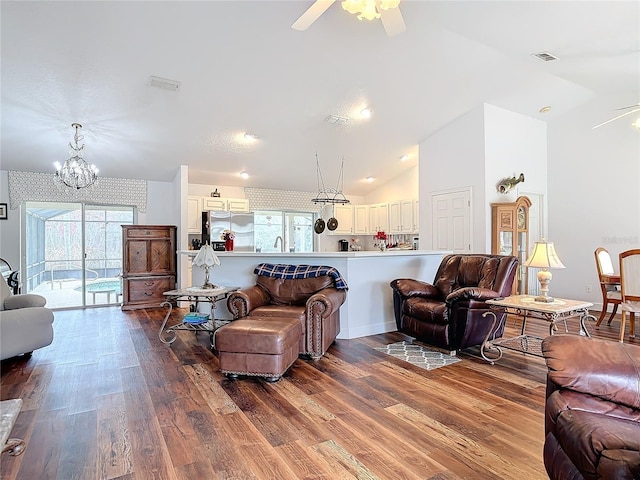 living room featuring sink, ceiling fan with notable chandelier, wood-type flooring, and vaulted ceiling