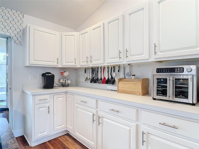 kitchen with dark hardwood / wood-style flooring, a textured ceiling, vaulted ceiling, and white cabinets