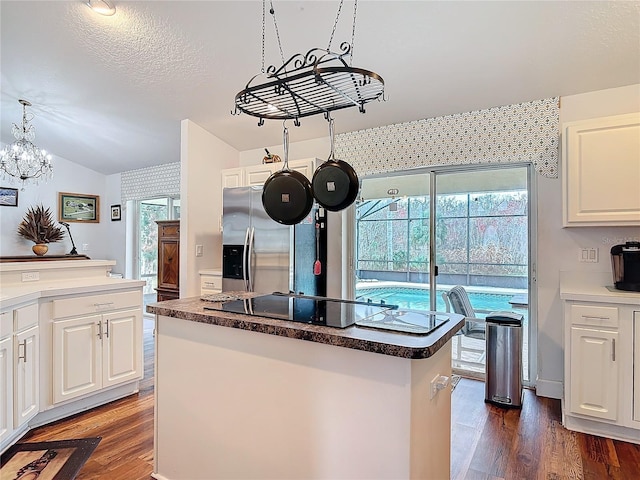 kitchen with lofted ceiling, white cabinets, a center island, stainless steel fridge with ice dispenser, and black electric cooktop