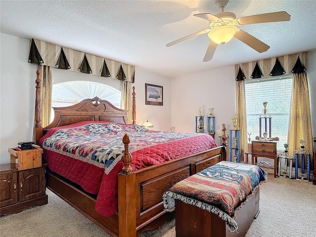 bedroom with ceiling fan, light carpet, and a textured ceiling