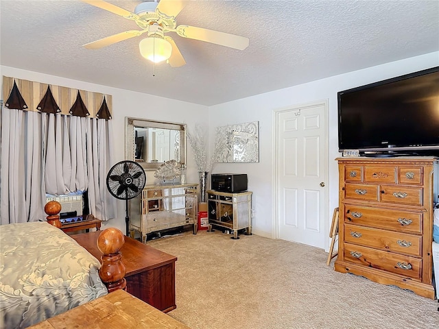 bedroom with ceiling fan, light colored carpet, and a textured ceiling