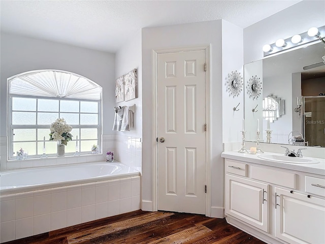 bathroom featuring vanity, wood-type flooring, shower with separate bathtub, and a textured ceiling