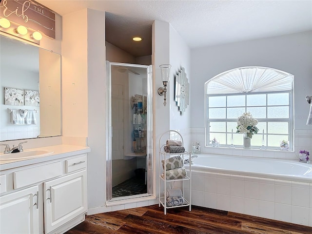 bathroom featuring vanity, hardwood / wood-style flooring, plus walk in shower, and a textured ceiling