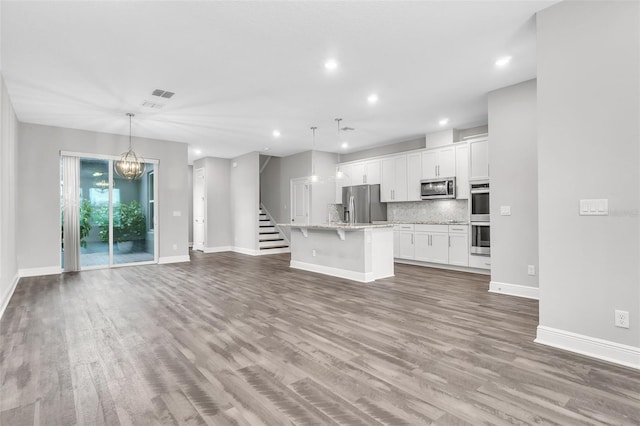 unfurnished living room with a notable chandelier and wood-type flooring