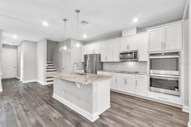 kitchen featuring sink, white cabinetry, decorative light fixtures, an island with sink, and stainless steel appliances