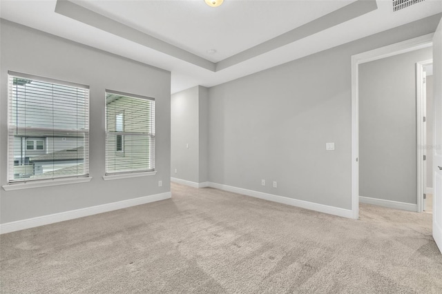 empty room featuring light carpet and a tray ceiling