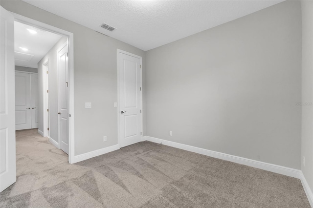 unfurnished bedroom featuring light colored carpet and a textured ceiling