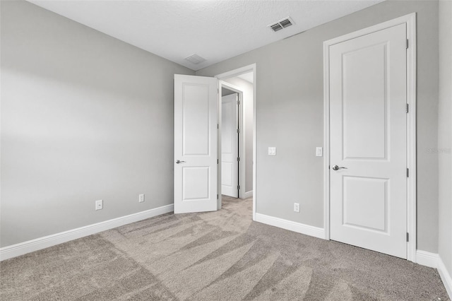 unfurnished bedroom with light colored carpet and a textured ceiling