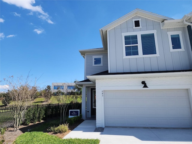 view of front of house with board and batten siding, concrete driveway, fence, and a garage