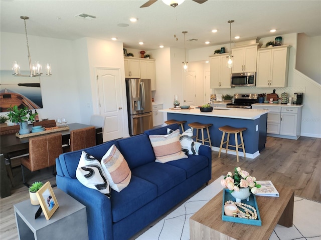 living room featuring light wood-style flooring, recessed lighting, visible vents, baseboards, and a ceiling fan