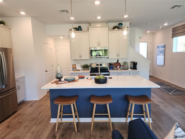 kitchen featuring appliances with stainless steel finishes, visible vents, a kitchen bar, and tasteful backsplash