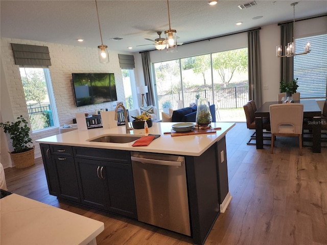 kitchen featuring light countertops, open floor plan, a sink, wood finished floors, and dishwasher