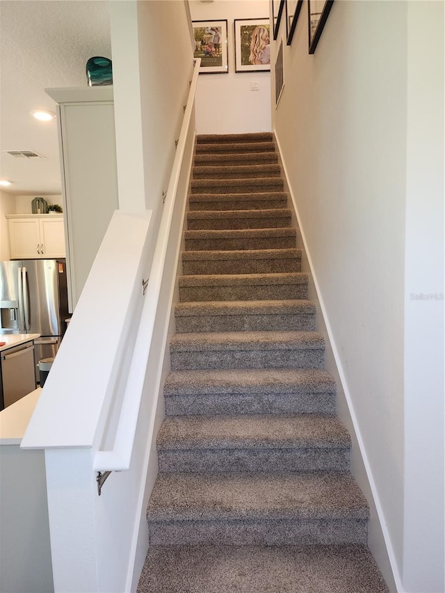 stairway with recessed lighting, visible vents, and baseboards