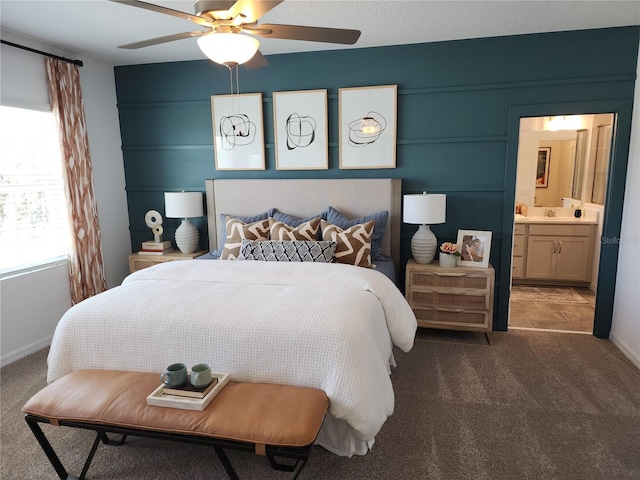 carpeted bedroom with ensuite bathroom, a ceiling fan, and baseboards