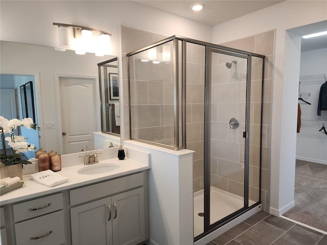 full bathroom with a stall shower, tile patterned floors, a walk in closet, and vanity