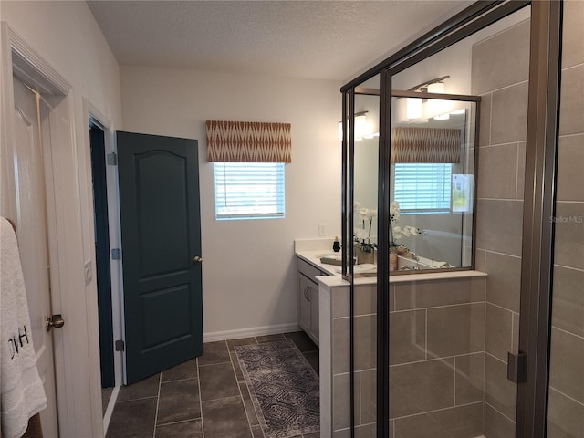 full bathroom featuring baseboards, tile patterned floors, a textured ceiling, vanity, and a shower stall