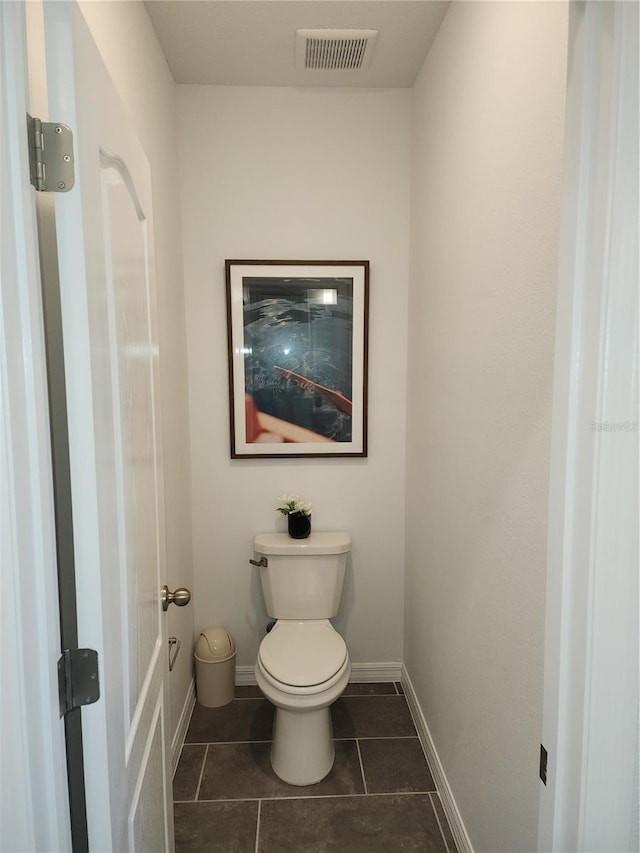 bathroom featuring baseboards, visible vents, toilet, and tile patterned floors