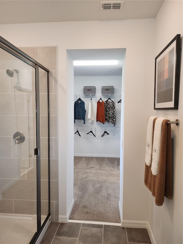 full bathroom with a shower stall, visible vents, a walk in closet, and baseboards