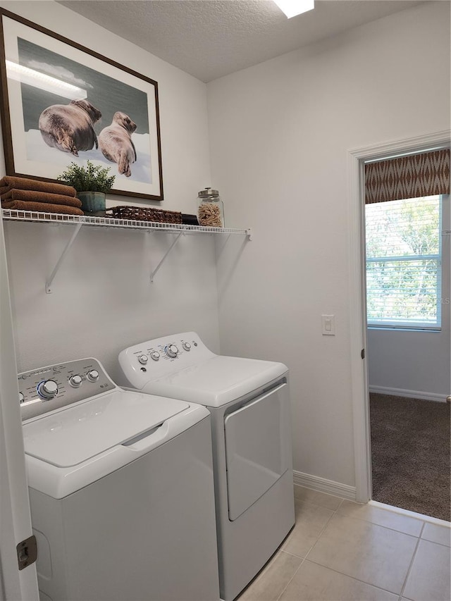 laundry room featuring light tile patterned floors, washing machine and dryer, a textured ceiling, laundry area, and baseboards