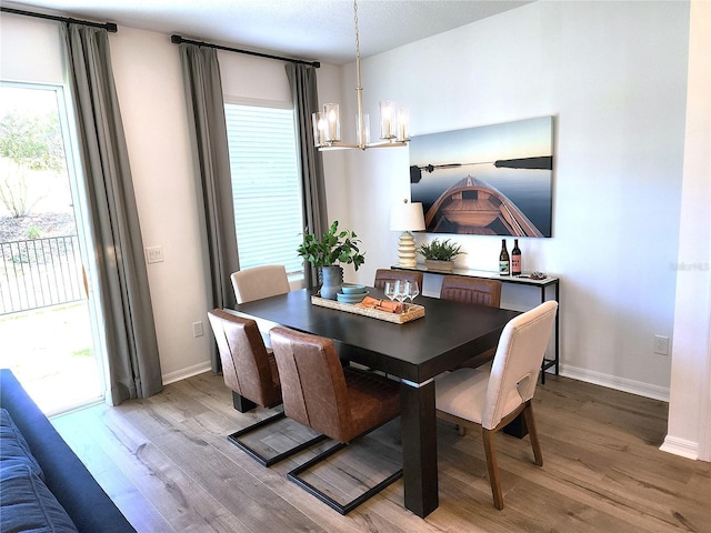 dining space with a notable chandelier, baseboards, and wood finished floors