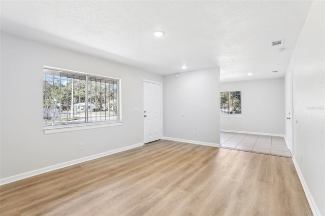 spare room featuring a textured ceiling and light wood-type flooring