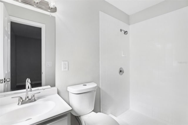 bathroom with vanity, a tile shower, and toilet