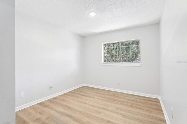 empty room with a textured ceiling and light wood-type flooring