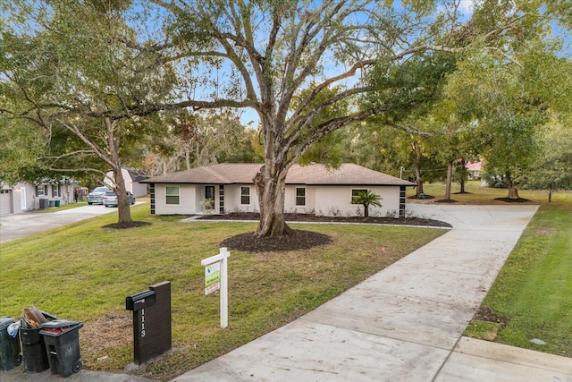 ranch-style home featuring driveway, a front yard, and stucco siding