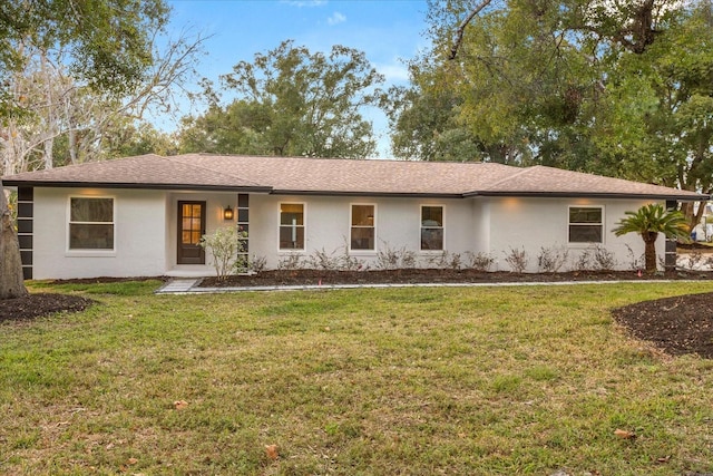 ranch-style house with a front lawn, a shingled roof, and stucco siding