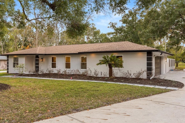 ranch-style house featuring a front lawn, a garage, driveway, and stucco siding