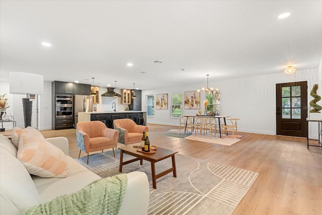 living room with a notable chandelier, recessed lighting, visible vents, baseboards, and light wood-type flooring